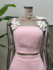 Mannequin wearing a pink dress with white floral embellishments and pearl necklace.