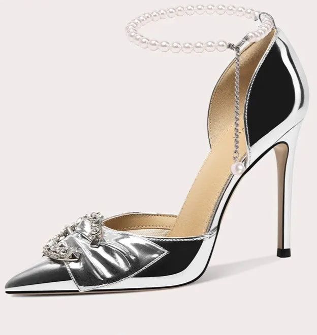 Silver high-heeled shoe with decorative chain on a white background