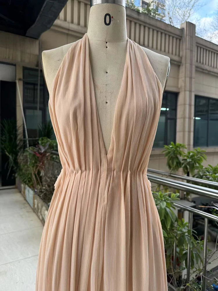Beige dress on a mannequin outdoors with buildings and plants in the background
