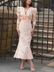 Woman wearing a floral dress standing in front of an iron gate.