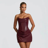 Woman wearing a strapless burgundy dress against a plain background