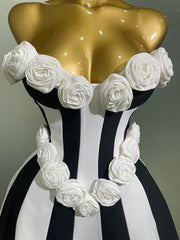 Mannequin torso with gold top and black and white striped skirt, adorned with white floral decorations.