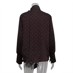Black shirt with white polka dots on a mannequin against a white background