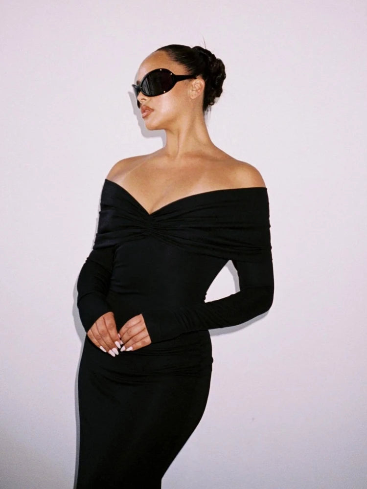 Woman wearing a black off-shoulder dress against a light background