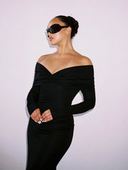 Woman wearing a black off-shoulder dress against a light background