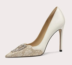 White high-heeled shoe with decorative brooch on a light gray background