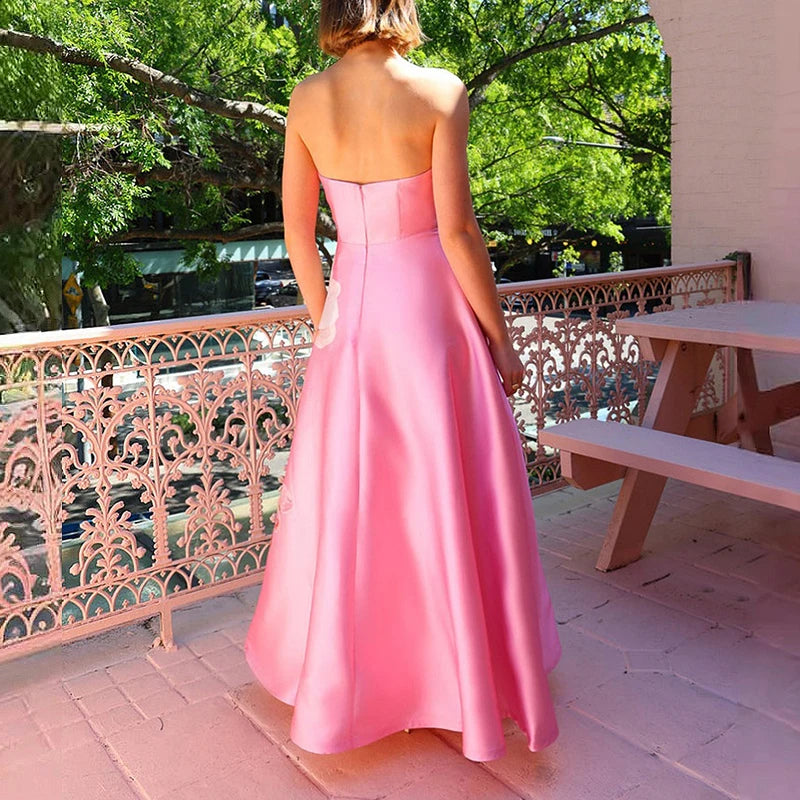 Woman in a pink strapless gown standing on a balcony with greenery in the background