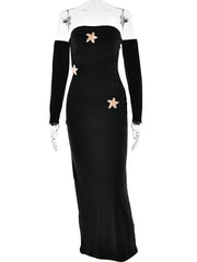 Black evening gown with floral embellishments on a mannequin against a white background