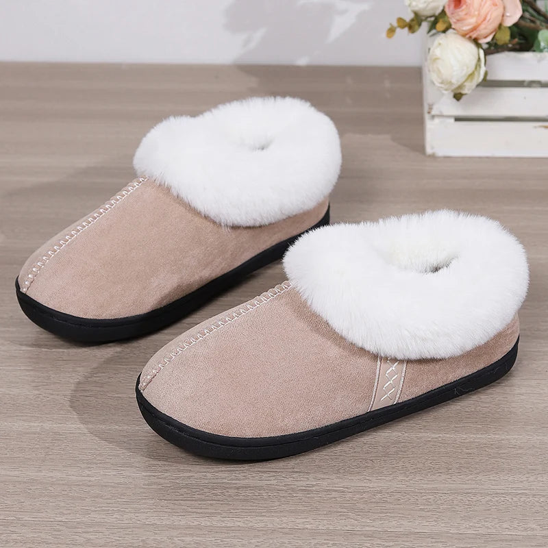 Pair of beige slippers with white fur trim on a wooden floor.
