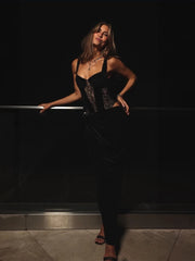 Woman in a black outfit posing against a dark background