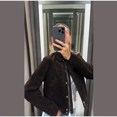 Person wearing a dark brown jacket taking a mirror selfie.