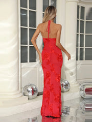 Woman wearing a red evening gown with floral details in an elegant indoor setting.
