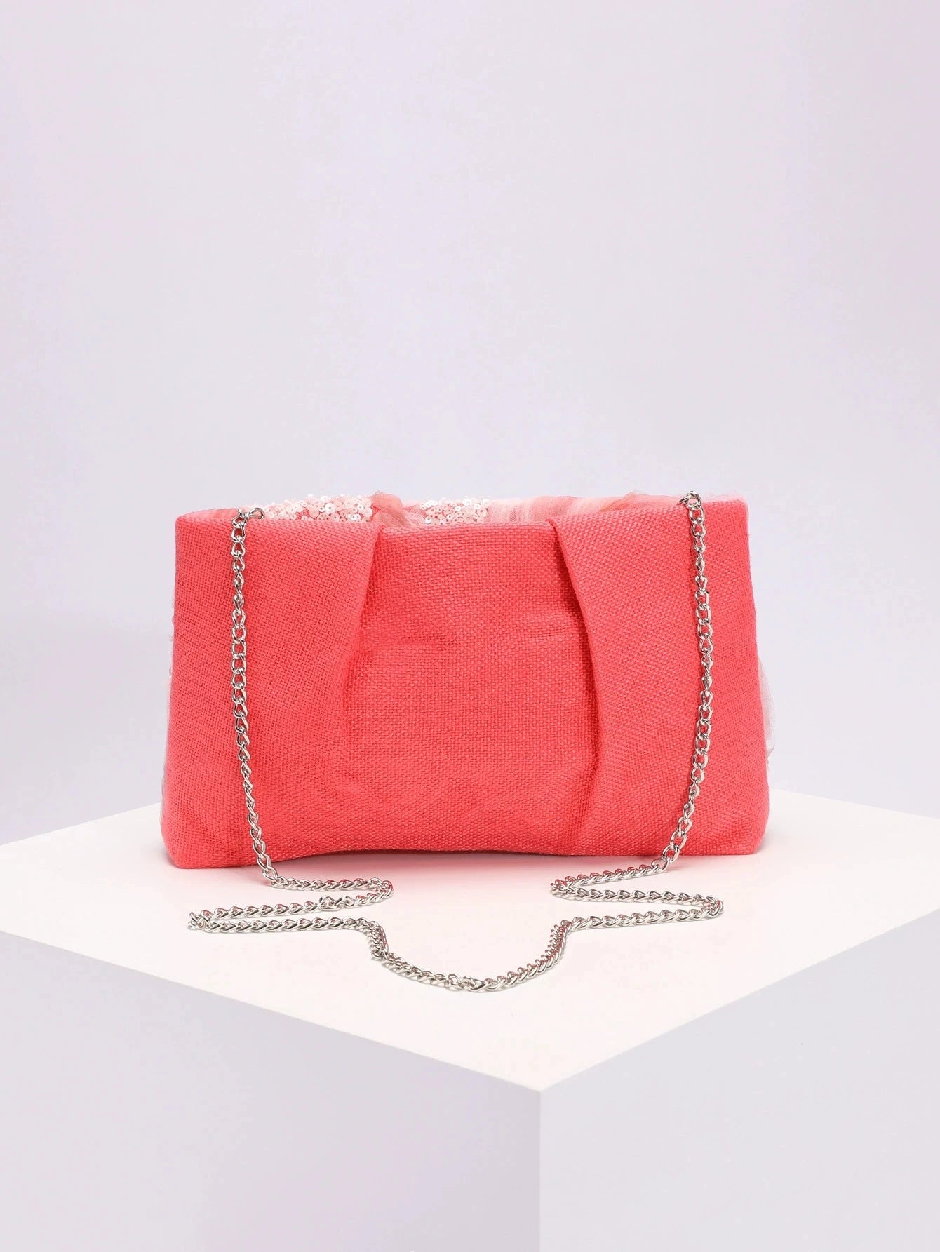 Pink clutch bag with a chain strap on a light gray background