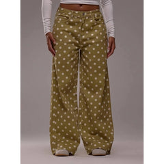Green pants with white polka dots worn by a person on a gray background