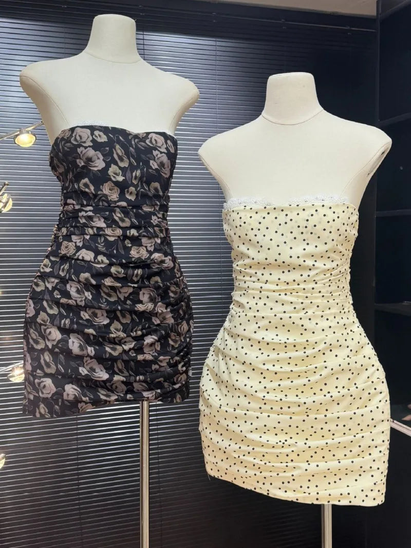 Two strapless dresses on mannequins against a dark background