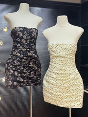 Two strapless dresses on mannequins against a dark background