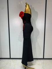 Black evening gown with red floral details on a mannequin against a white background