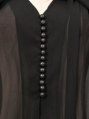 Close-up of a black garment with a vertical row of buttons on a plain background