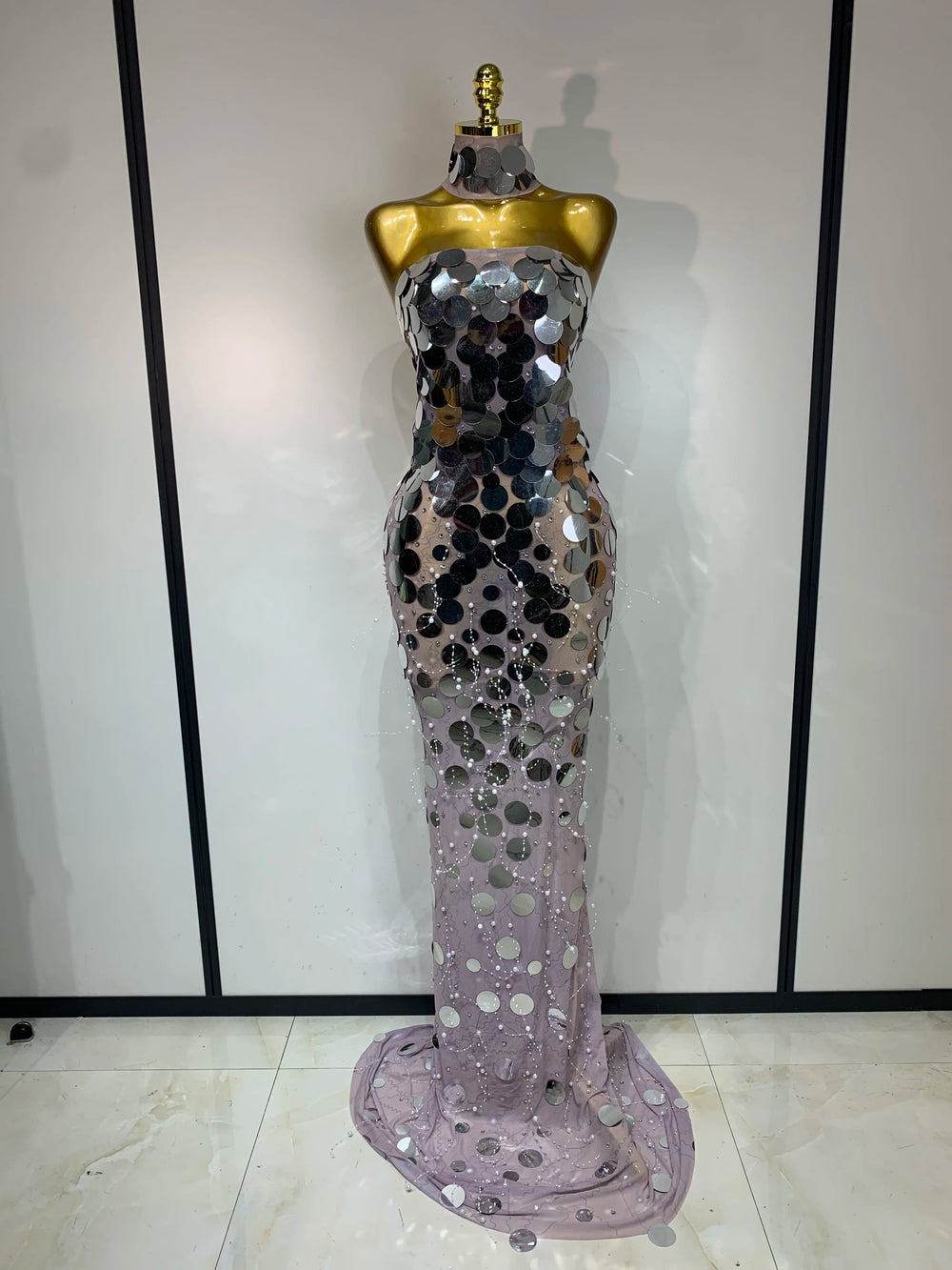 Mannequin wearing a silver sequin evening gown against a plain background