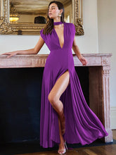 Woman in a purple evening gown with a high slit standing in a room with a mirror and fireplace.
