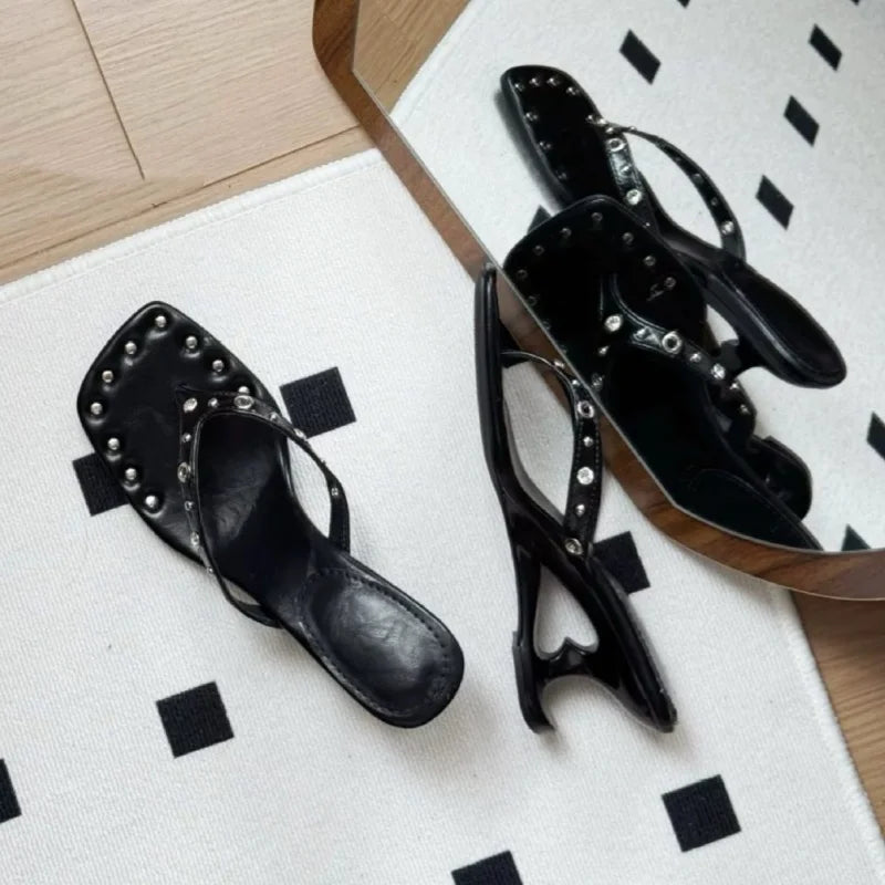 Black studded square toe flip flop sandals reflected in a mirror