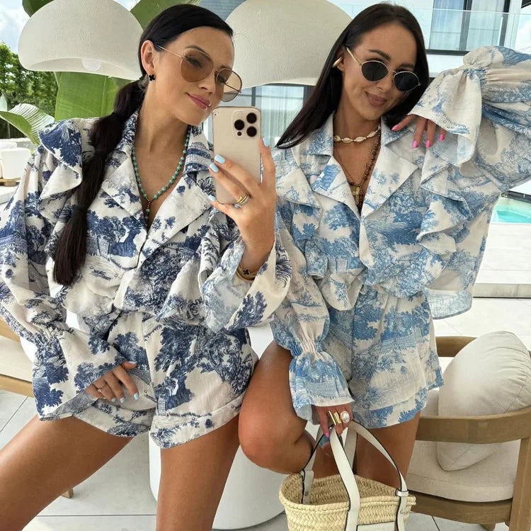 Two women in matching blue and white floral outfits taking a mirror selfie.