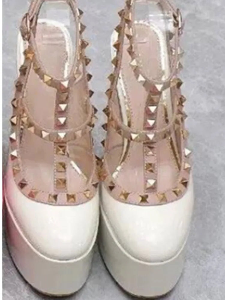 Pair of high-heeled sandals with gold studs on a light gray background