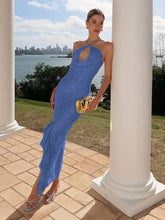Woman in a blue dress standing outdoors with a cityscape in the background