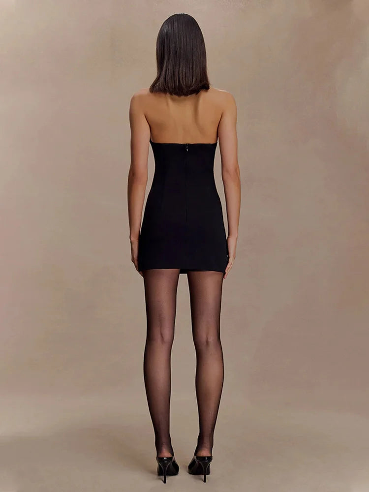 Woman wearing a black strapless dress against a beige background