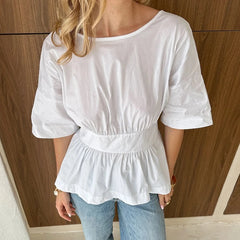 Person wearing a white blouse with a wooden panel background