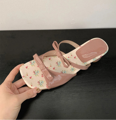 Pink sandal with floral pattern on a dark surface