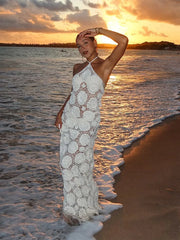 Woman in a white lace dress standing on a beach at sunset
