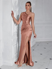 Woman in a rose gold evening gown standing in a white room with black and white tiled floor.