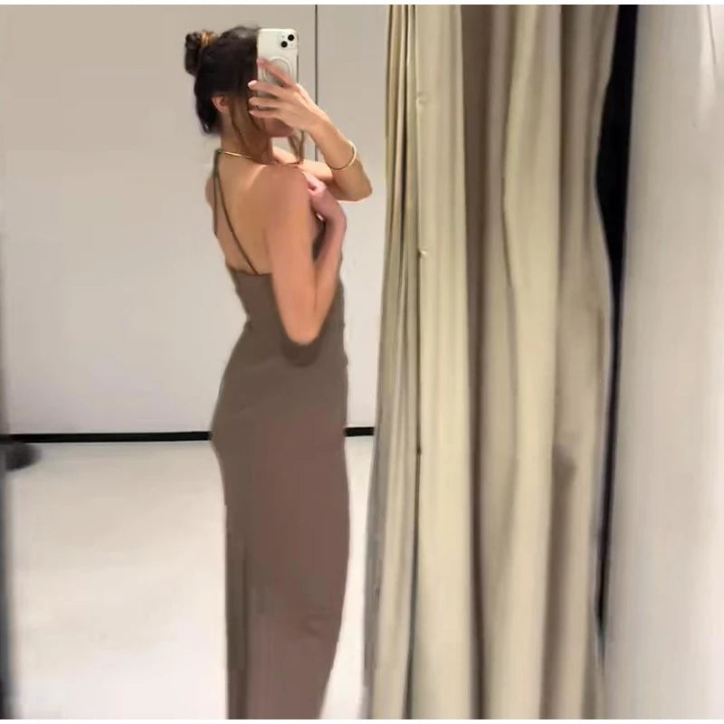 Woman taking a mirror selfie wearing a long dress in a minimalistic room.