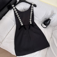 Black mini dress with embellished straps and velvet bows displayed on a mannequin