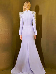 Woman wearing a light purple evening gown with embellished shoulders against a gold background