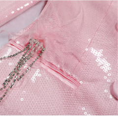 Close-up of a pink sequined garment with decorative elements.