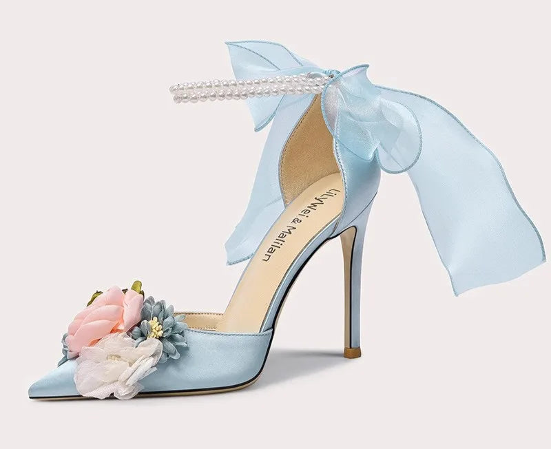 Light blue high-heeled shoe with floral decorations and a bow on a white background