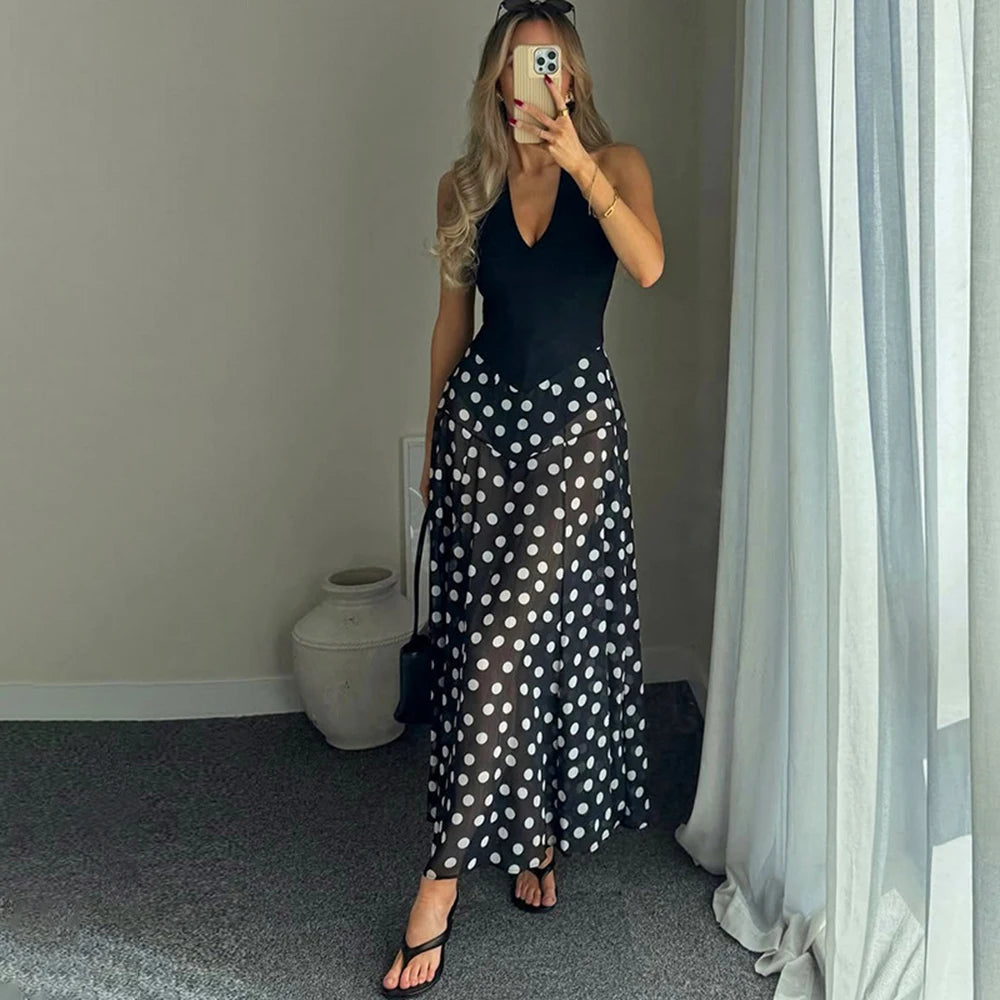 Back view of a person wearing a black polka dot maxi dress with a V-neck.