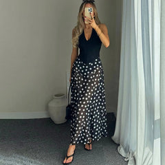 Back view of a person wearing a black polka dot maxi dress with a V-neck.