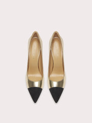 Pair of high-heeled shoes with gold bodies and black pointed toes on a light gray background