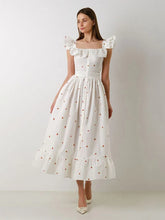 Woman wearing a white dress with ruffled sleeves against a plain background