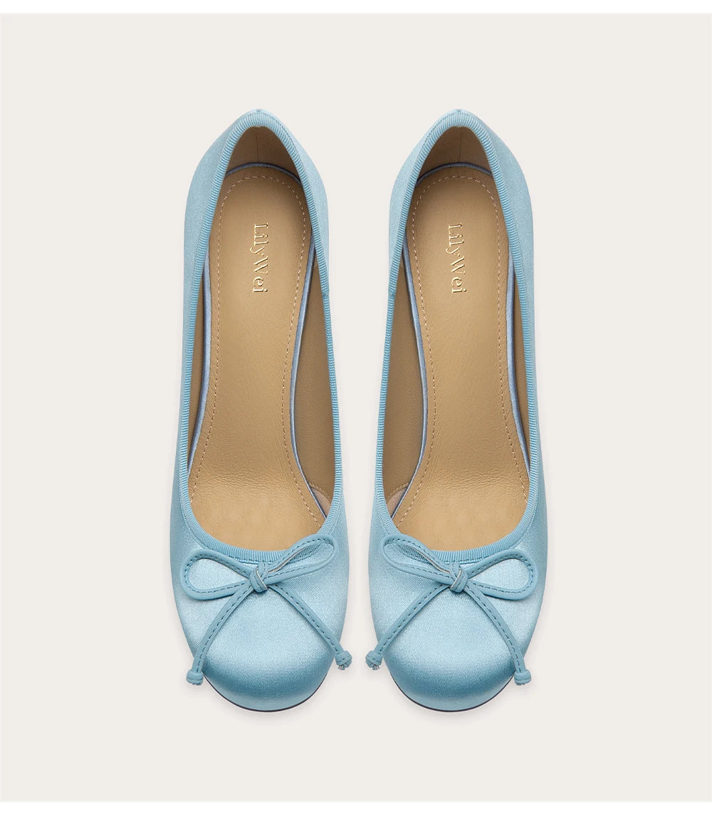 Pair of light blue shoes with bow details on a white background
