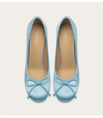 Pair of light blue shoes with bow details on a white background