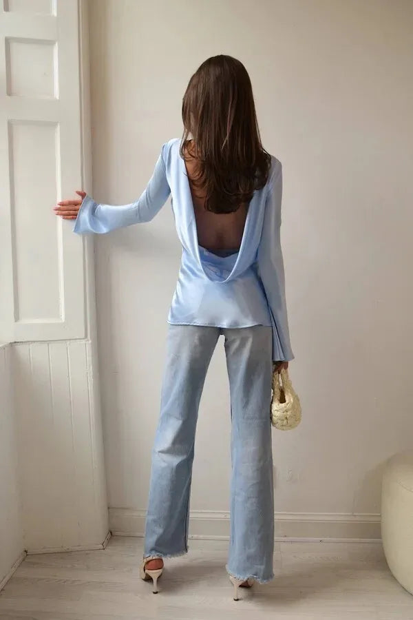 Woman in a light blue outfit standing in a room with a white door and wall.