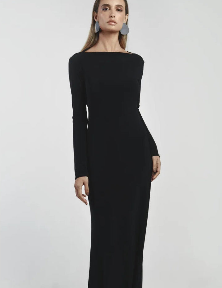 Woman wearing a black long-sleeve dress against a light gray background
