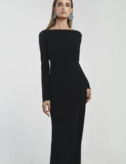 Woman wearing a black long-sleeve dress against a light gray background