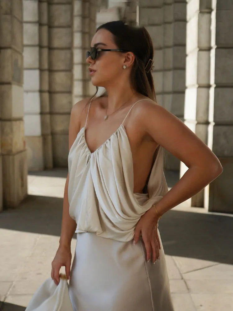 Woman in a light-colored dress standing outdoors with stone architecture in the background
