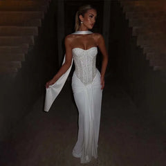 Woman in a white strapless gown with a cape against a dark background