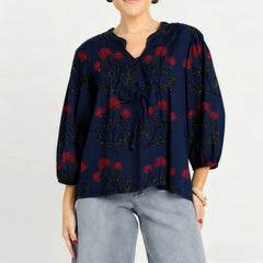 Woman wearing a navy blue blouse with red floral patterns on a white background